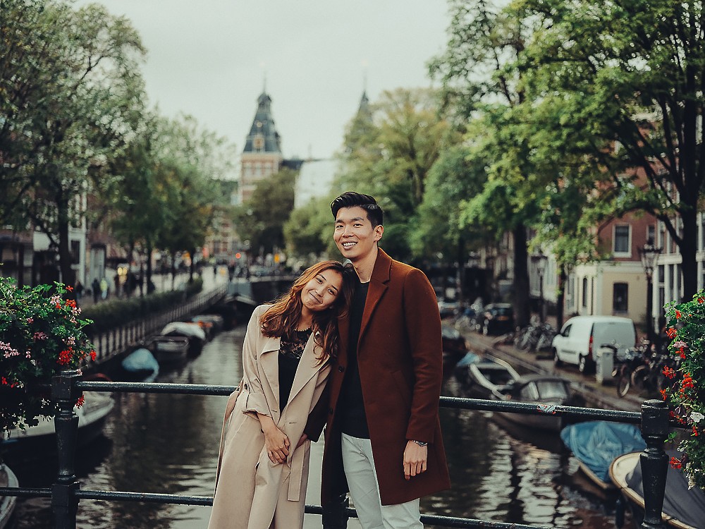 Vrouw legt haar hoofd op de schouder van haar partner op een grachtenbrug met het Rijksmuseum erachter, een spontane fotoshoot in Amsterdam