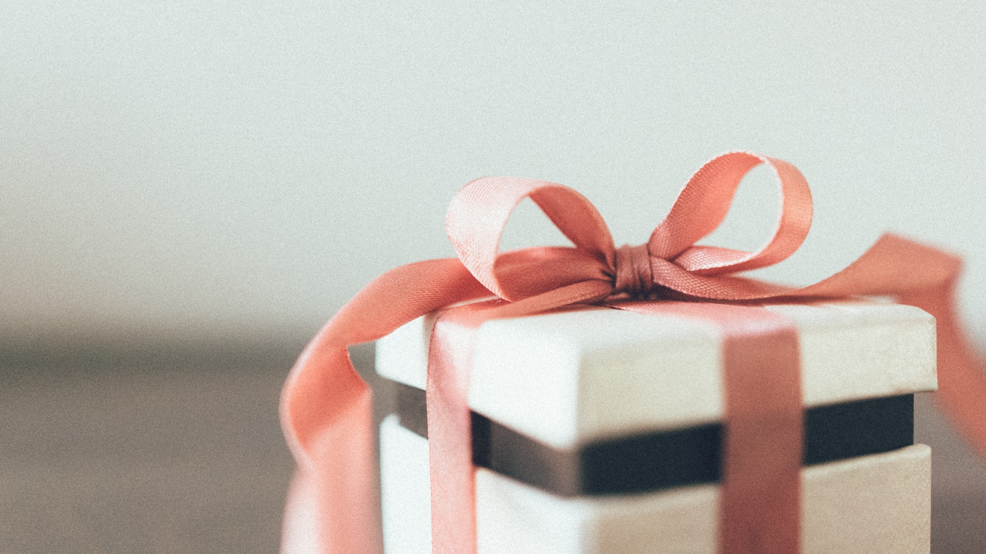 White gift box tied with a peach ribbon bow, a photoshoot gift card from a professional photographer in Amsterdam