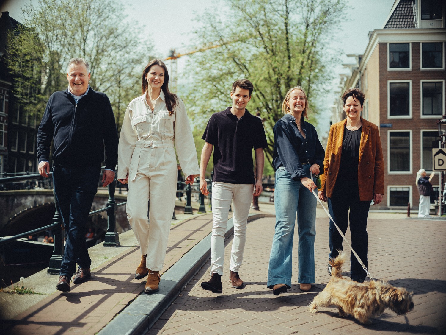 Gezin even later op dezelfde brug, de terriër trekt vooruit terwijl de ouders op hun trouwdag naast elkaar lopen