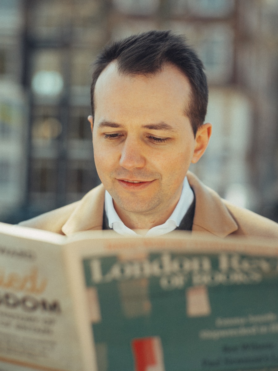 Close-up van een man die de London Review of Books leest in zacht zonlicht, een ontspannen portret
