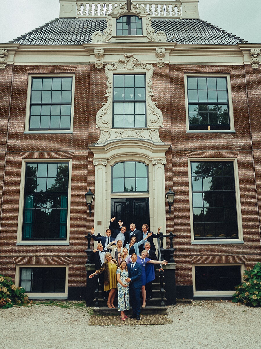 Family waving from the steps of a grand country house during an anniversary photoshoot