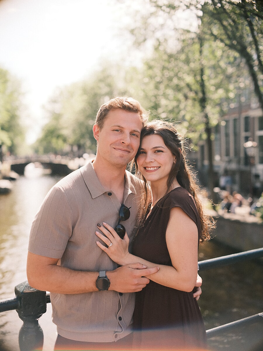 Newly engaged couple standing relaxed on an Amsterdam canal bridge just after the surprise proposal