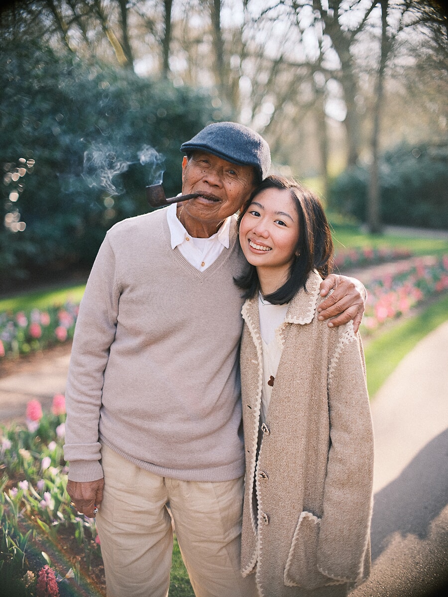 Grandfather and granddaughter cheek to cheek beside the tulip beds of an Amsterdam park