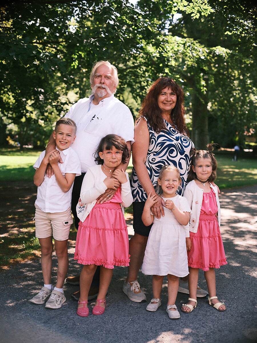 Grandparents with their four grandchildren under the trees of an Amsterdam park, a family anniversary in summer