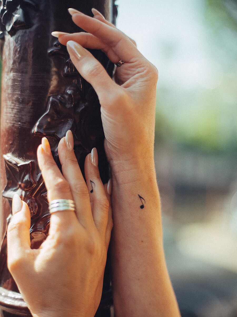 Two hands with matching music note tattoos in place of engagement rings