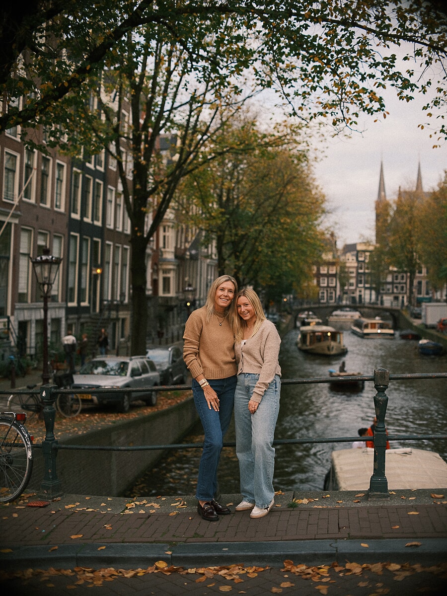 Mother and teenage daughter on an Amsterdam canal bridge in autumn, natural family photography by the water