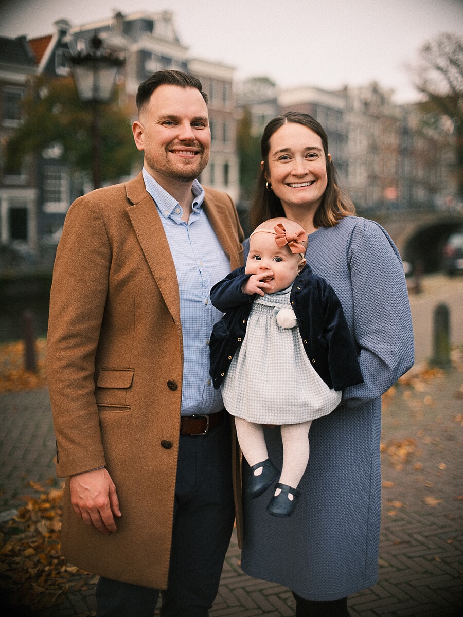 Parents holding their baby daughter beside an Amsterdam canal, a tender frame from their family photography session