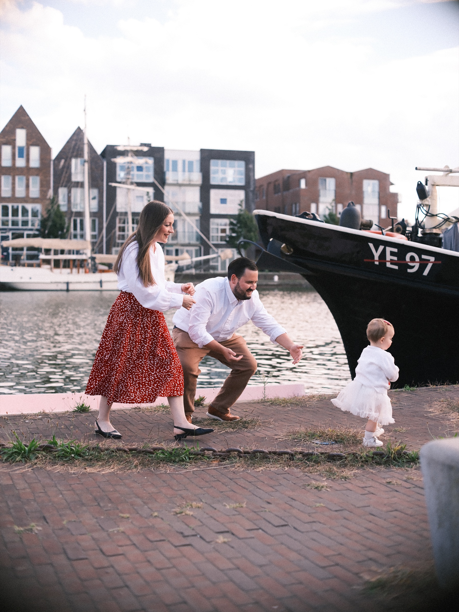 Dreumes in een tulen rokje zet stapjes richting de zwarte vissersboot YE 97 in Haarlem, met haar ouders gehurkt achter haar