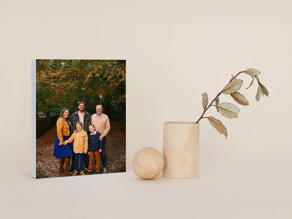 Canvas of a family with two children on an autumn forest path, standing next to a wooden vase with a leafy branch and a wooden ball