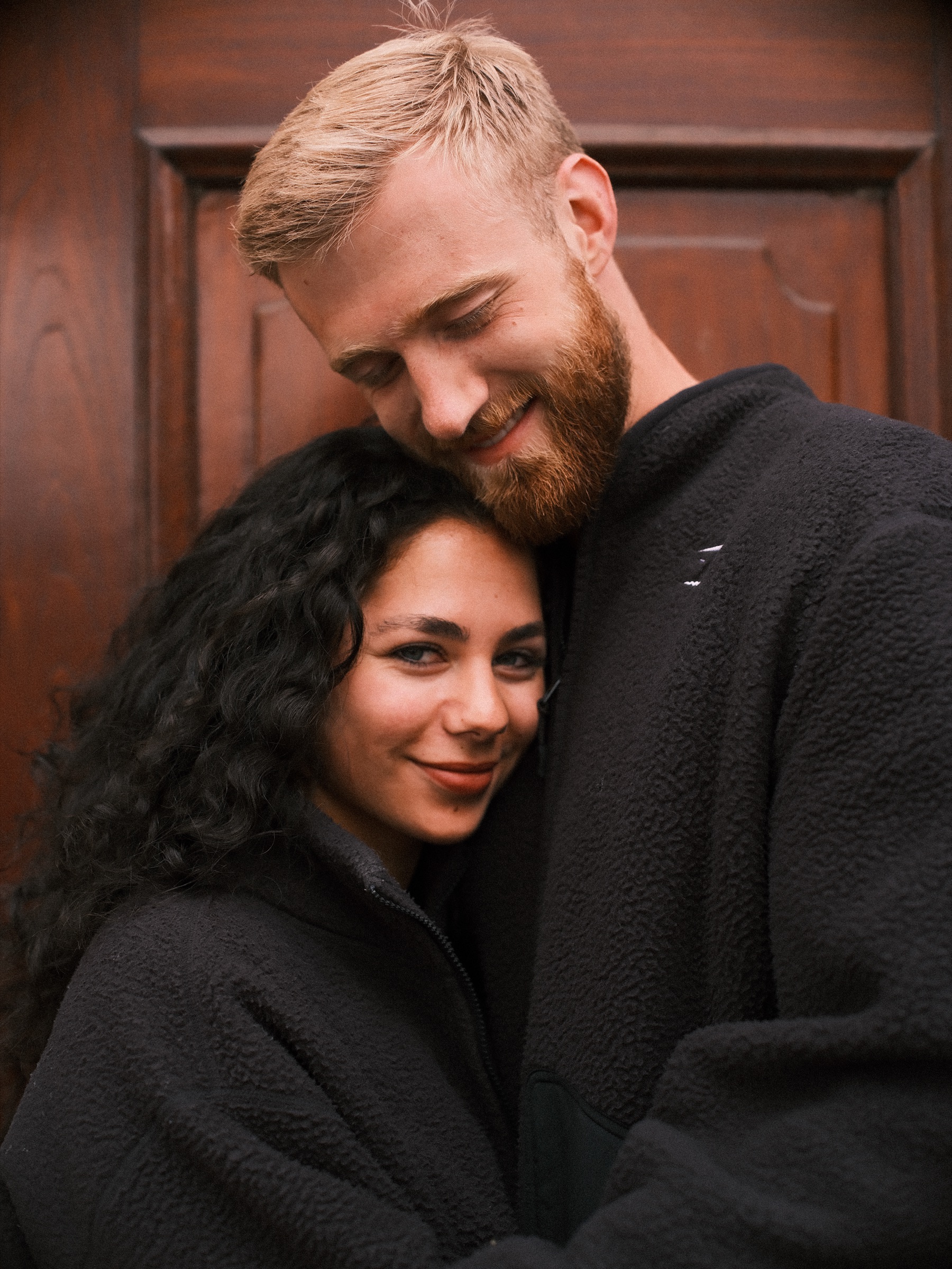 Vrouw legt haar wang op de borst van haar vriend en lacht naar de camera, het laatste beeld van hun wandeling in het zwart