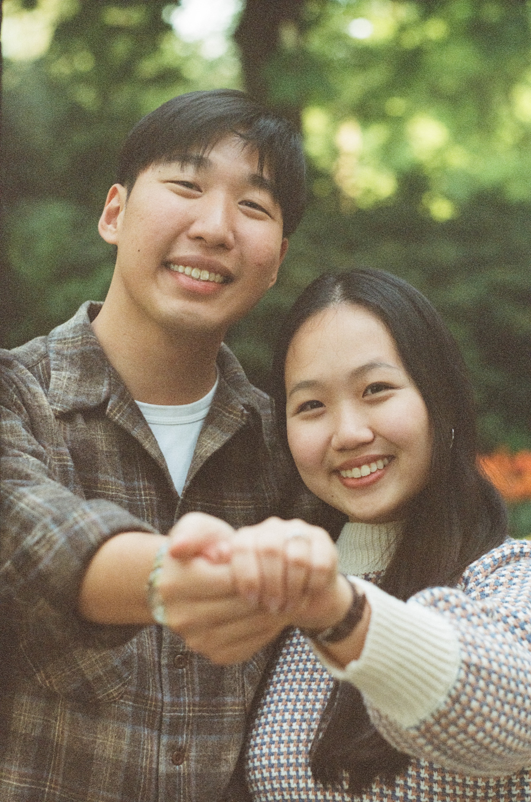 Close portrait on film of the engaged couple smiling and holding their joined hands toward the camera at Keukenhof
