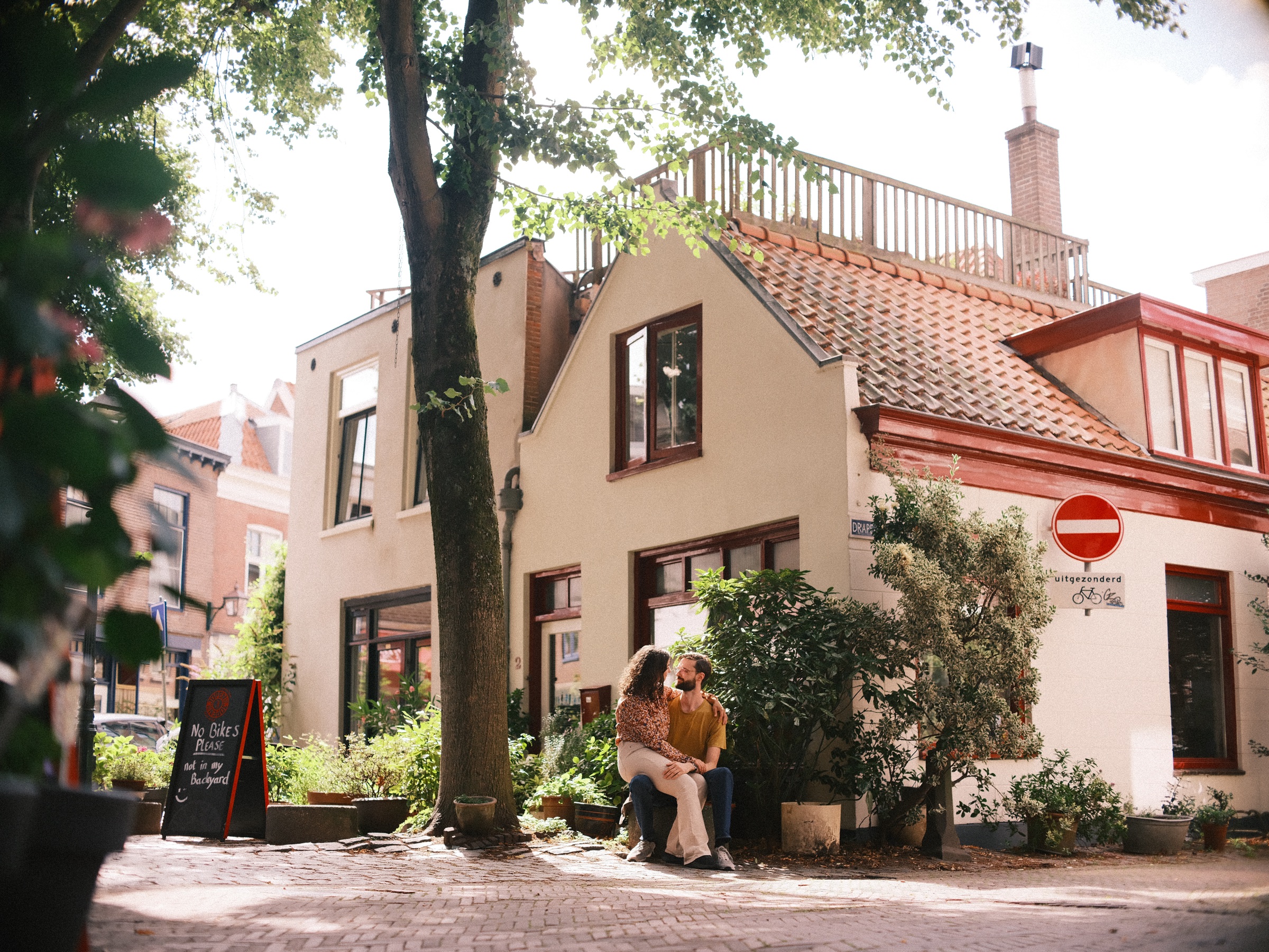 Stel op een bankje onder een hoge boom op het pleintje van de Vijfhoek in Haarlem, het laatste beeld van hun eerste zomerwandeling