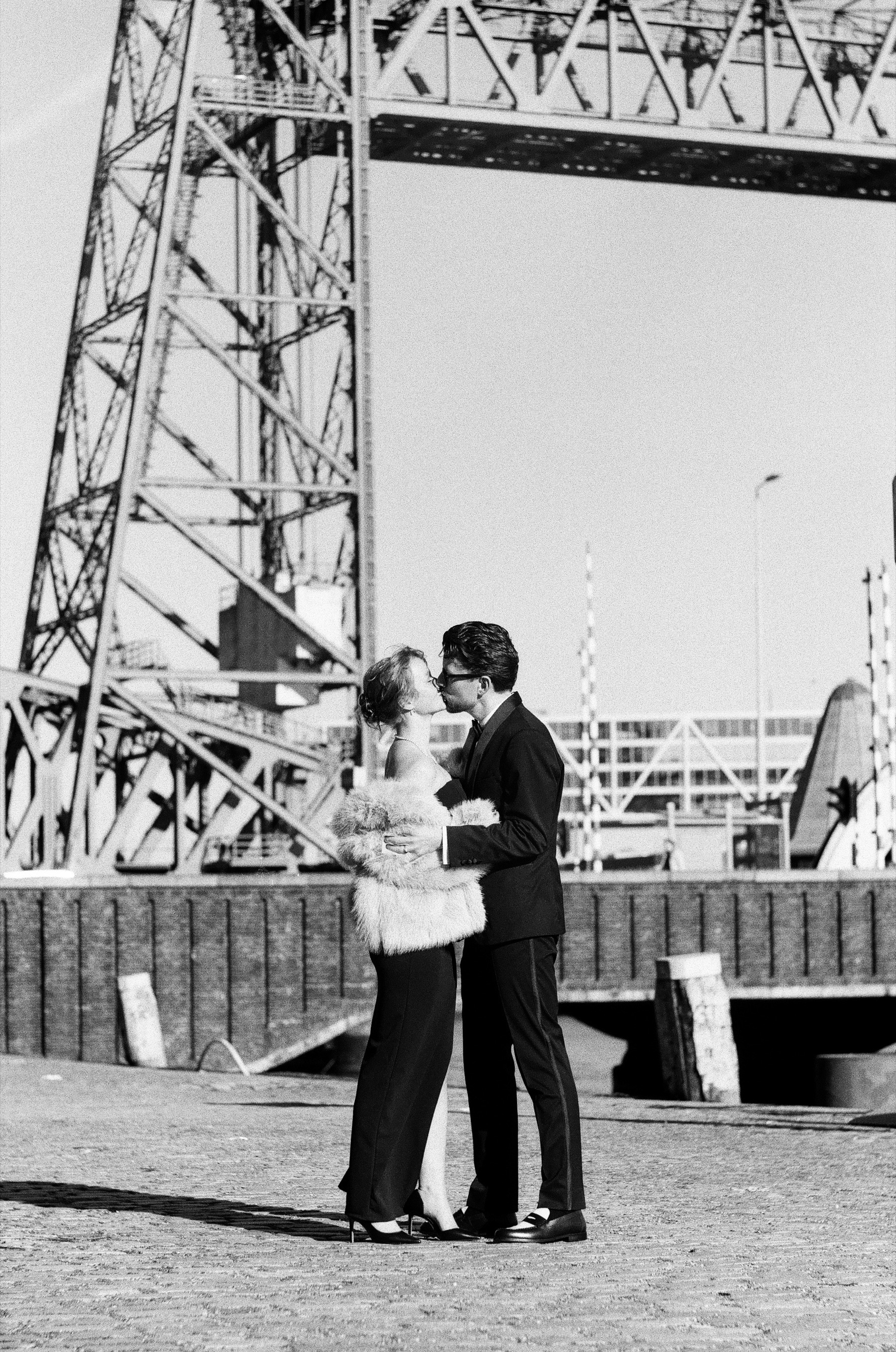 Couple kissing on an open square under the steel tower of De Hef, the old lift bridge in Rotterdam, the last frame of the proposal