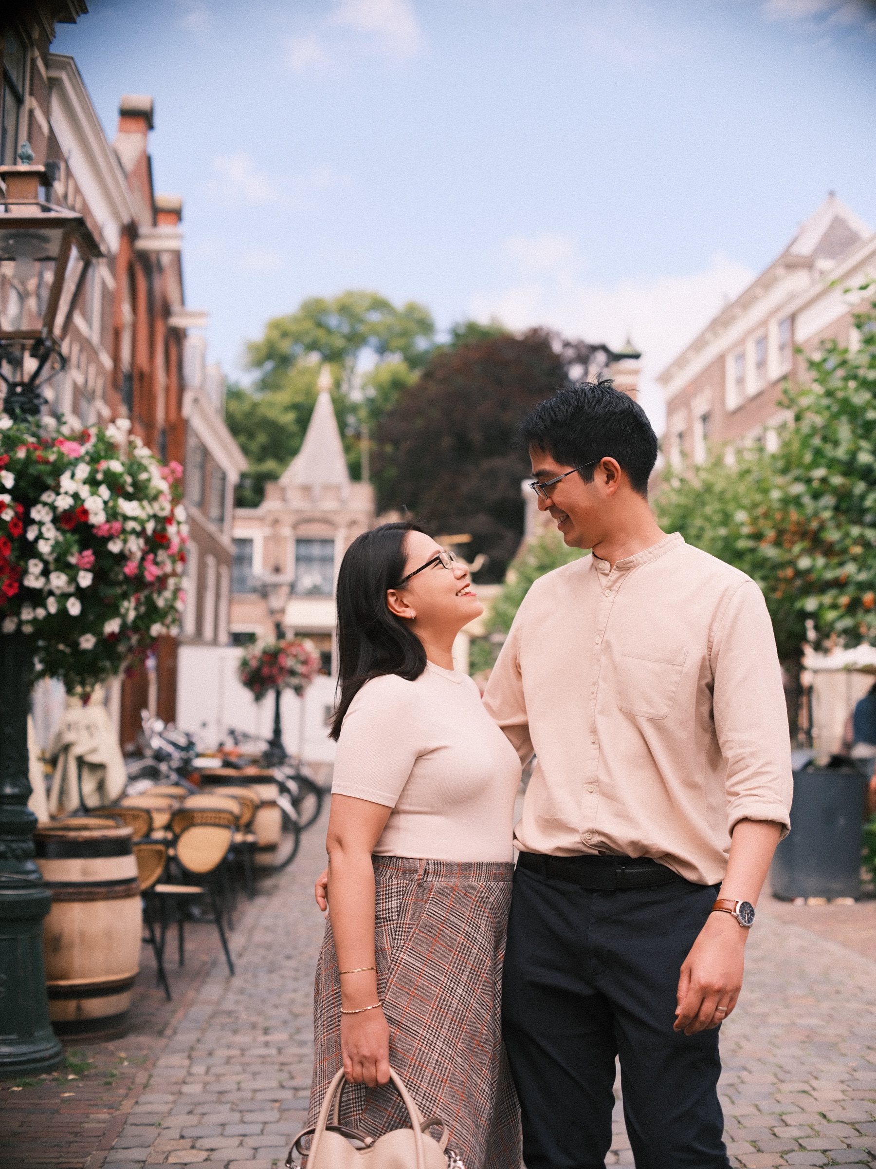 She looks up at him and laughs in the middle of the lane, a long checked skirt and a cream shirt, the turrets of the Burcht gate behind them