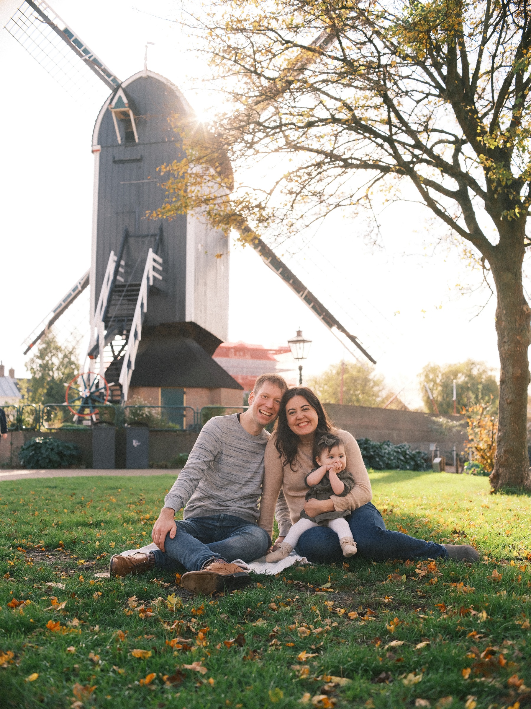 Family photos on the lawn below Molen De Put in Leiden, the parents and their baby sitting in the grass as the low sun shines past the mill