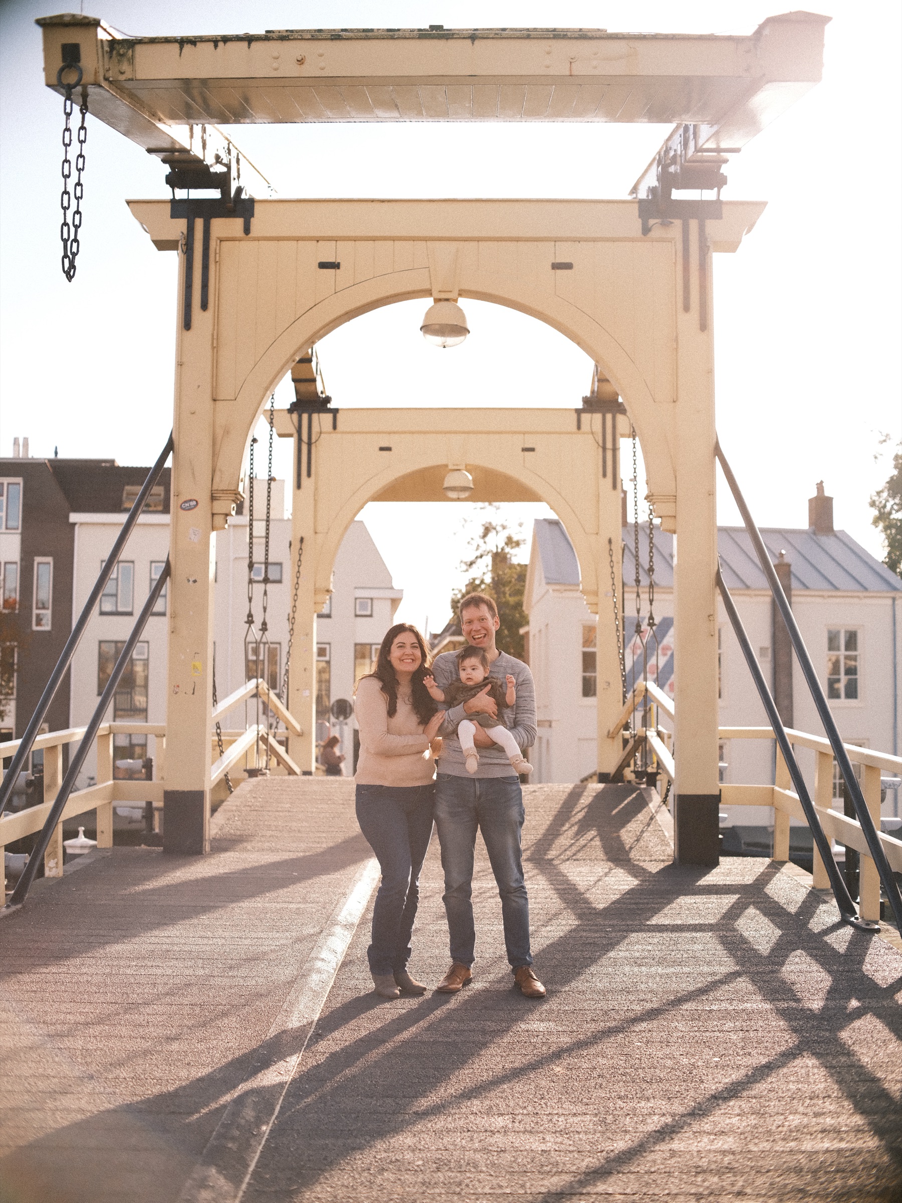 Family of three in the middle of the Rembrandtbrug in Leiden, the white wooden drawbridge backlit by the low autumn sun