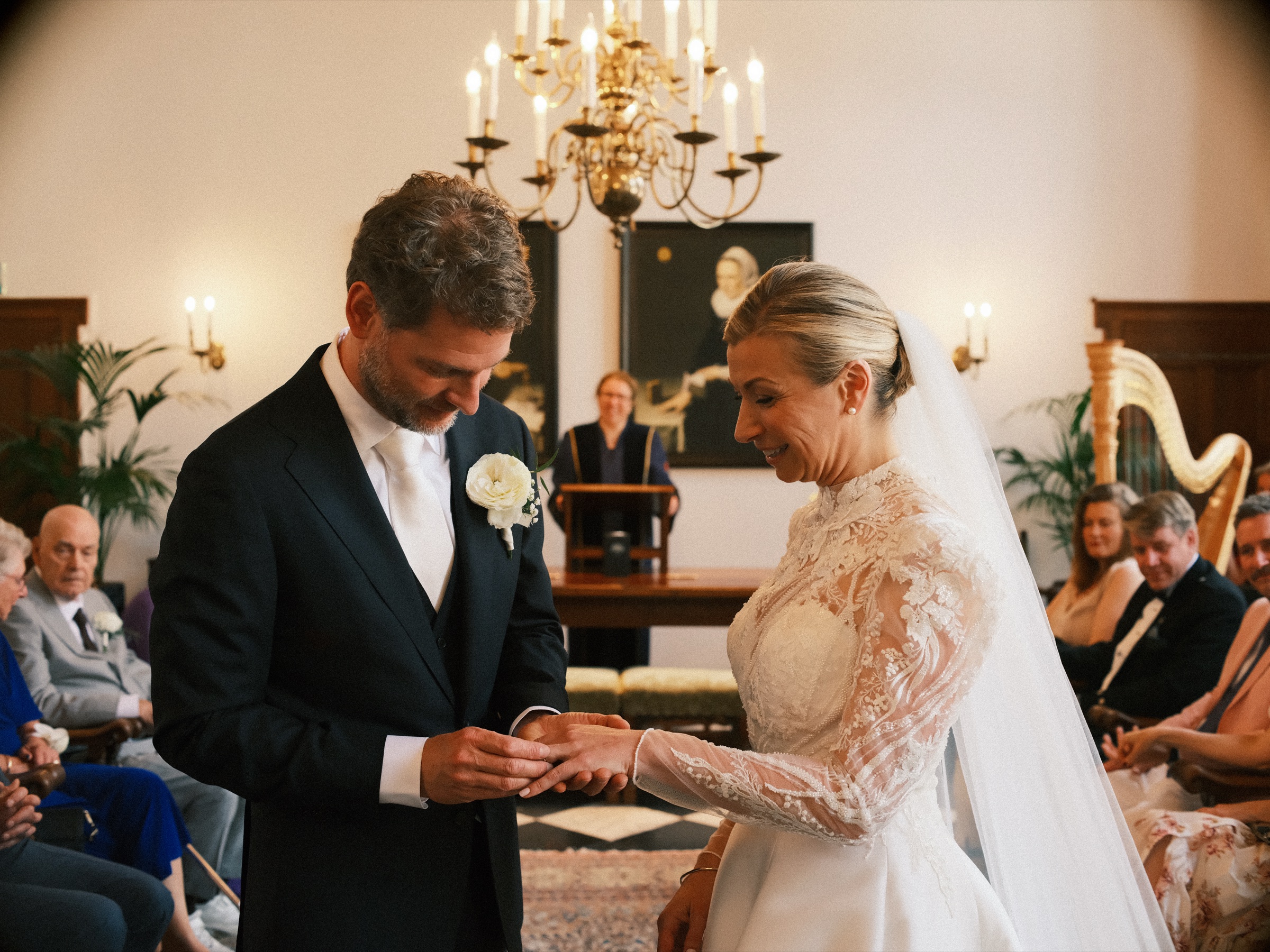 Bruidegom schuift de ring om de vinger van de bruid, met een gouden harp en een palm achter hen in het stadhuis van Delft
