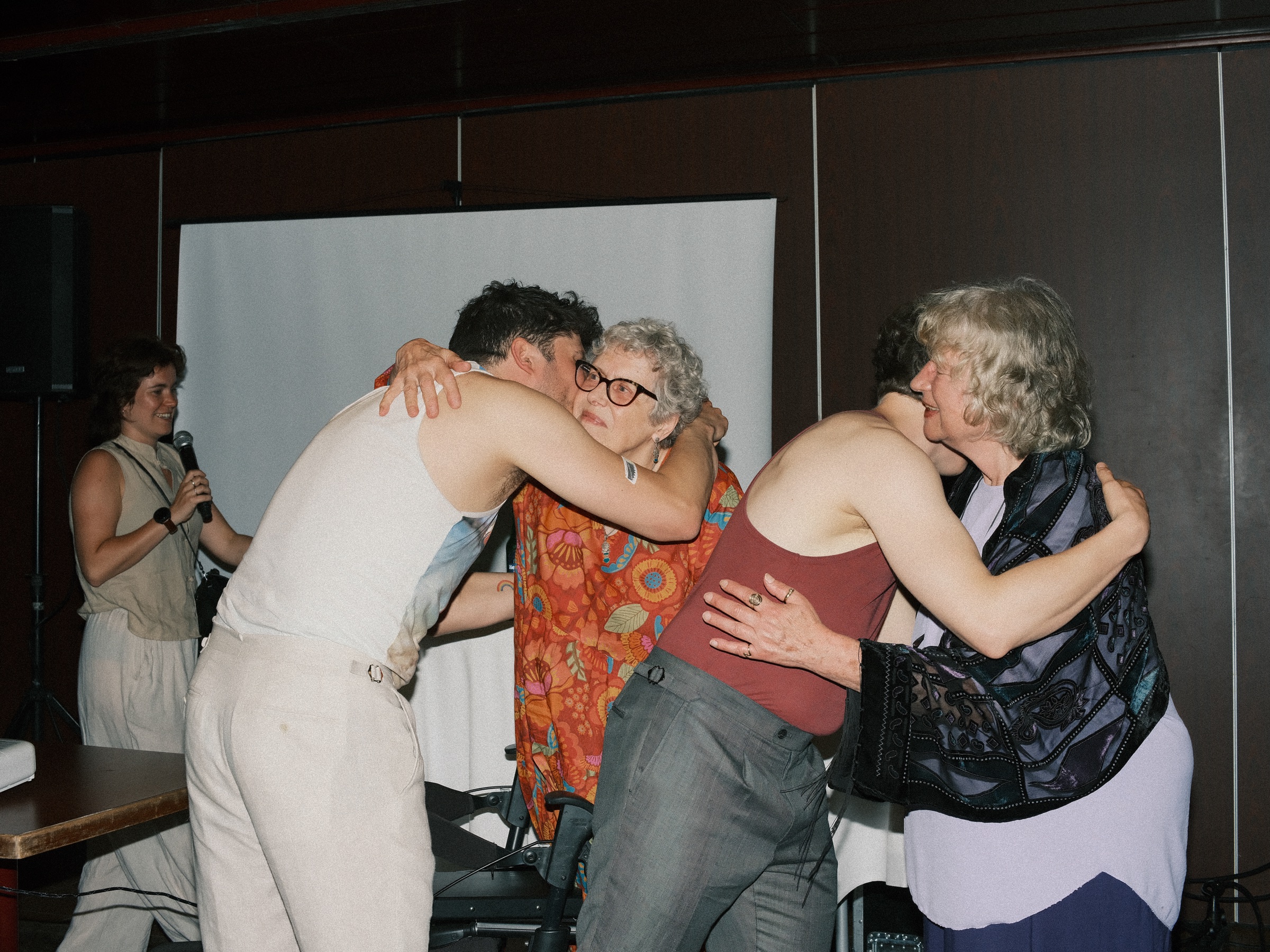 The grooms hugging two older women after their reading, the last frame of a long and happy same-sex wedding day