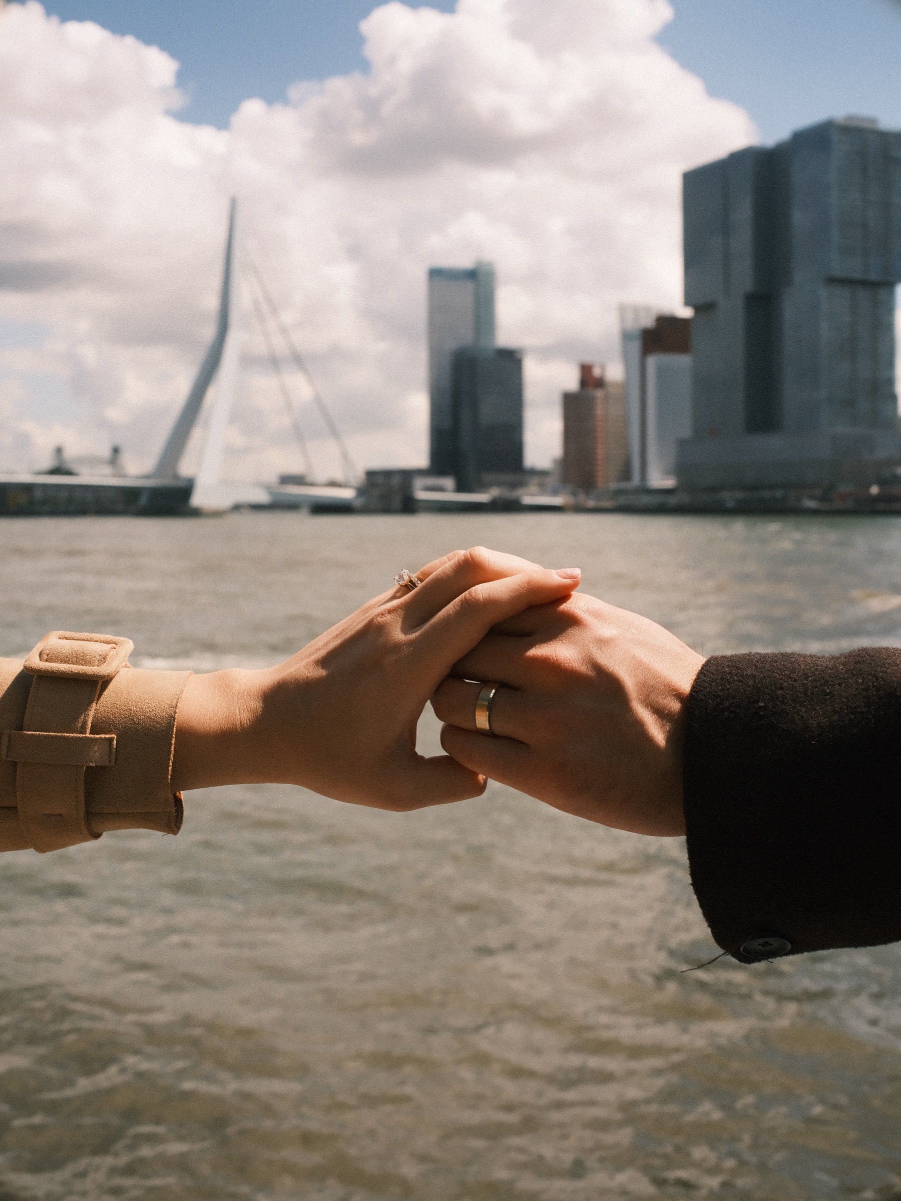 Their hands meeting above the water of the Maas, her engagement ring in the sun and the Erasmusbrug just beside them