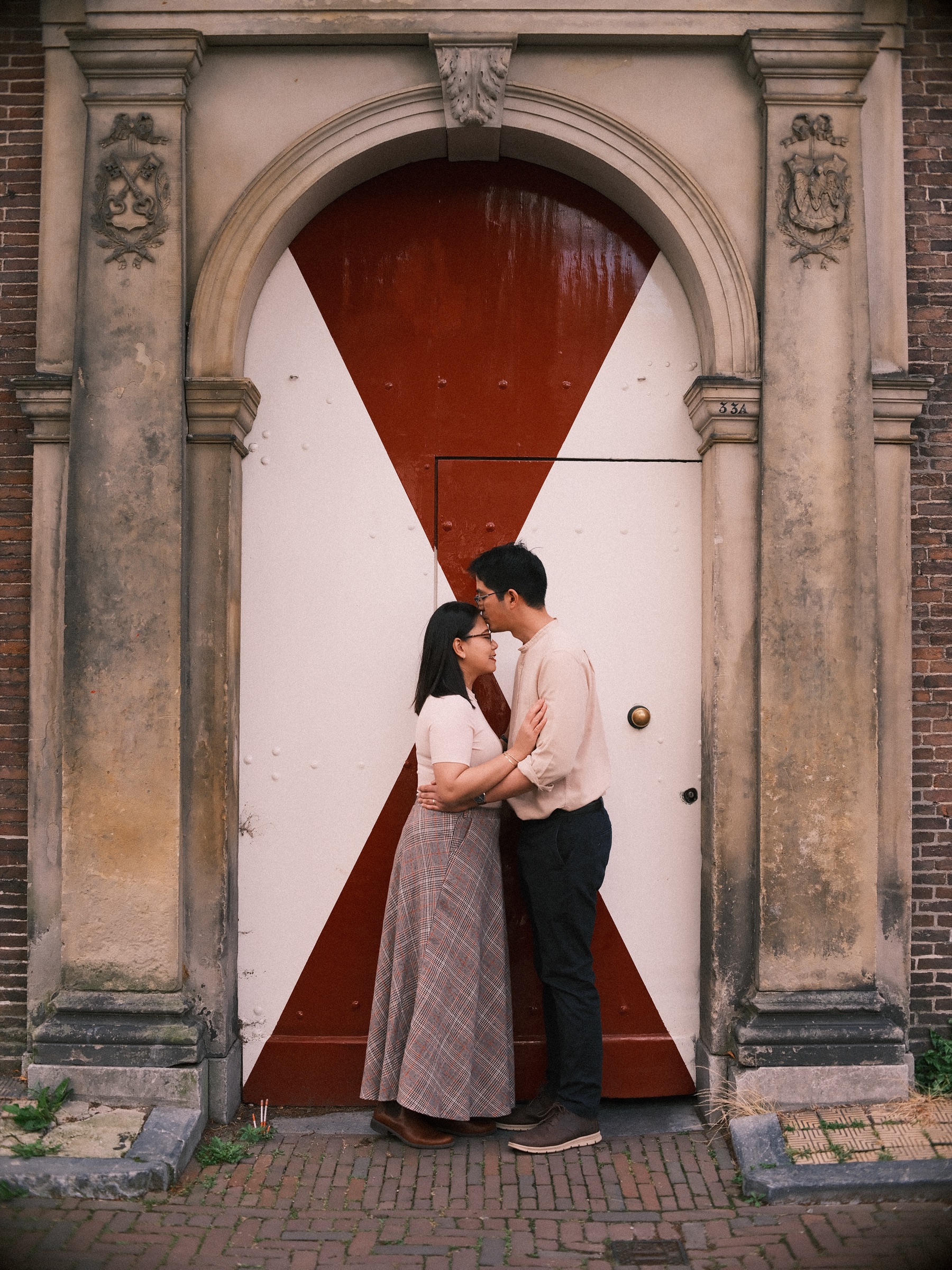 Kiss in the center of a stone gateway whose doors are painted in red and white triangles, coats of arms carved on each side