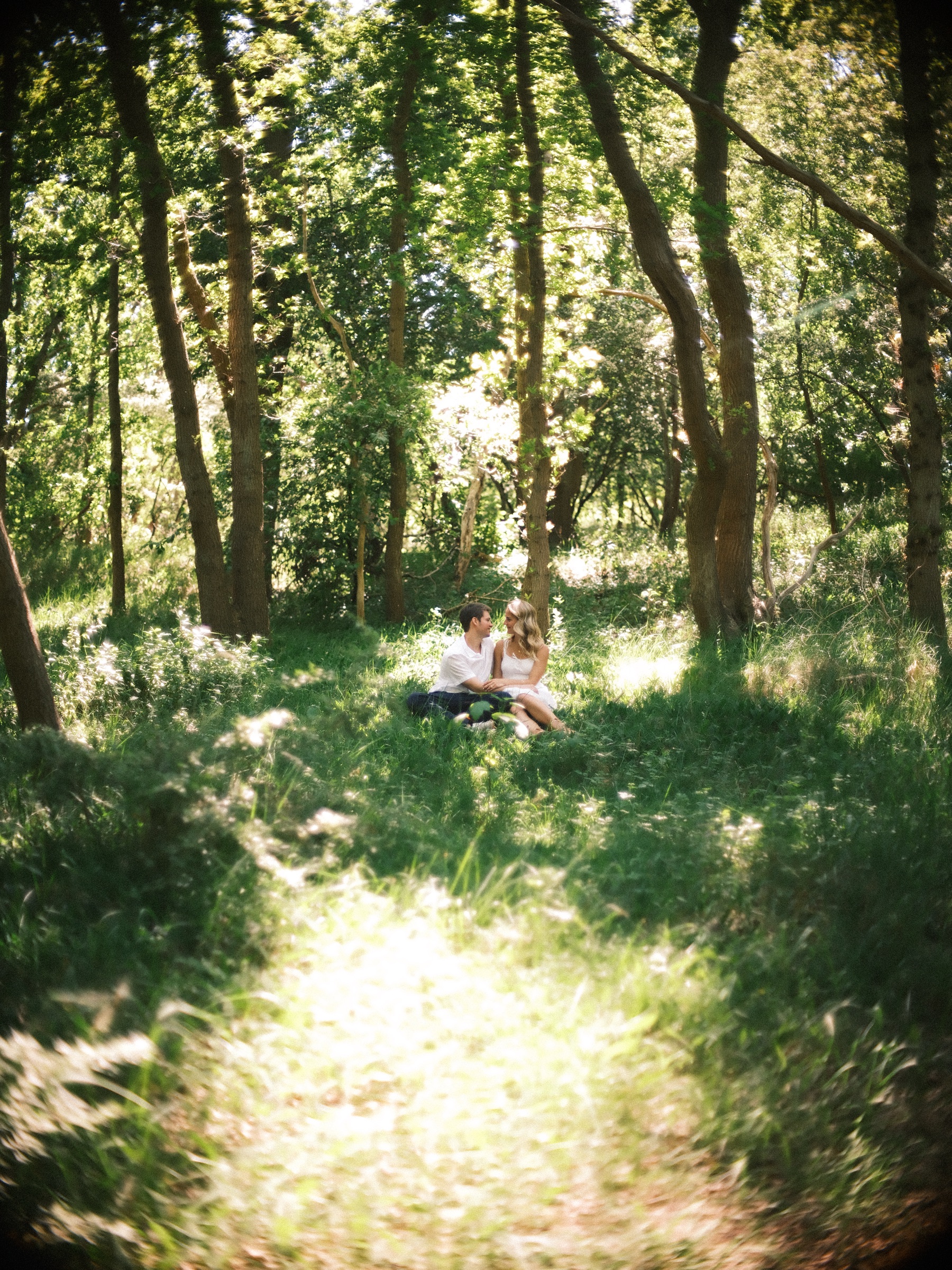 De laatste verlovingsfoto in de duinen: het stel klein in het hoge gras, met een zonnig pad dat naar hen toe loopt