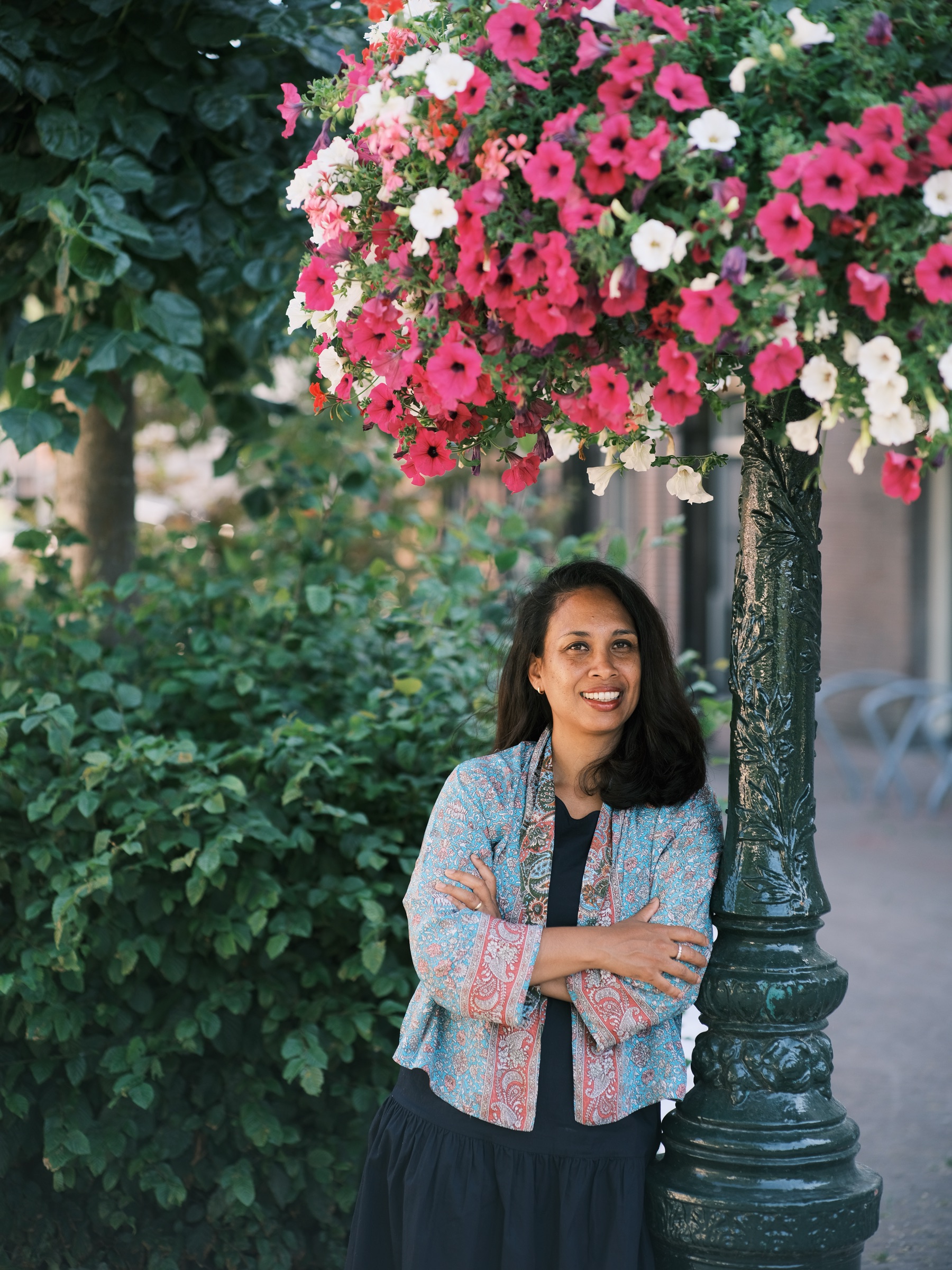 Vrouw met loshangend haar en zonder bril glimlacht naast een sierlijke groene lantaarnpaal, het laatste beeld van een zomerse middag in Leiden