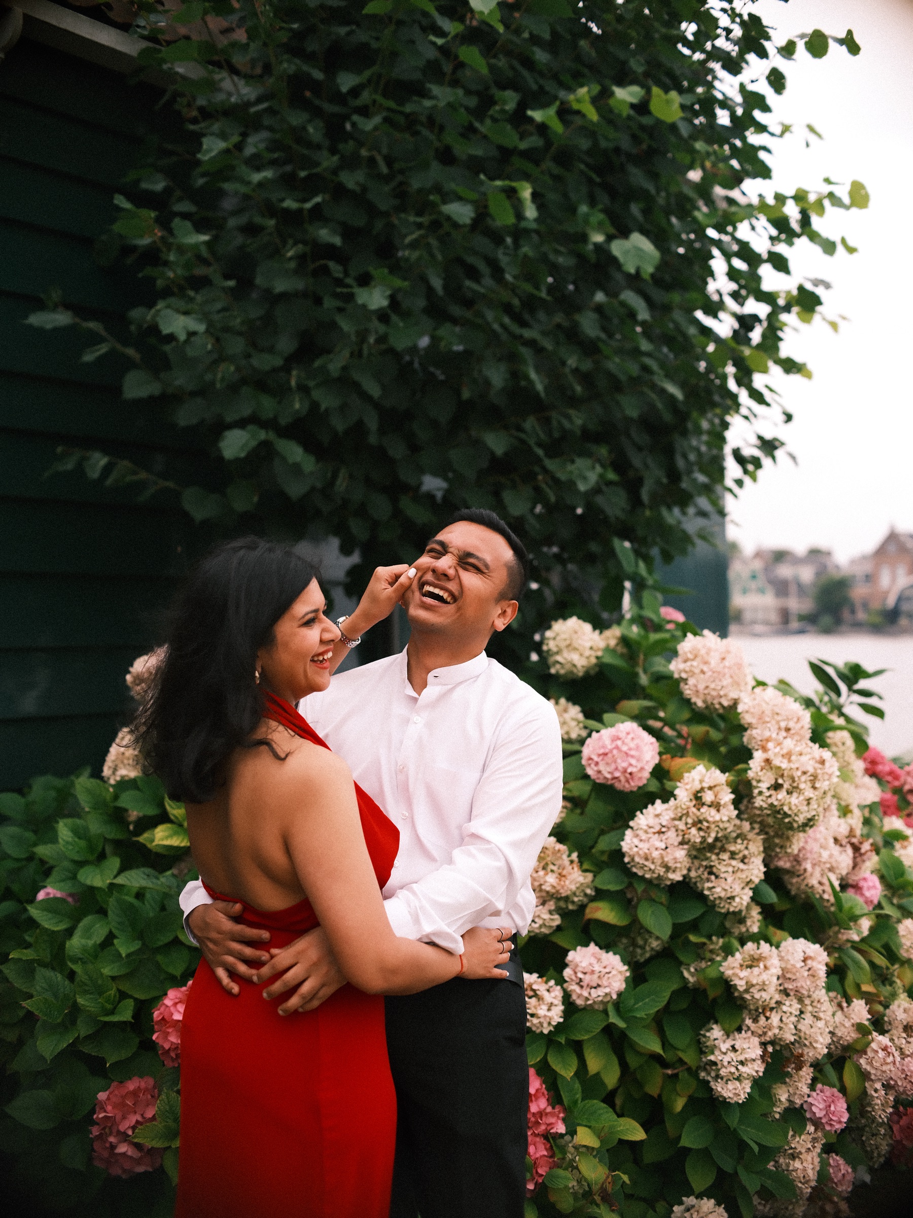 She laughs and touches his face as they hold each other among pink and cream hydrangeas, the Zaan and its houses soft behind