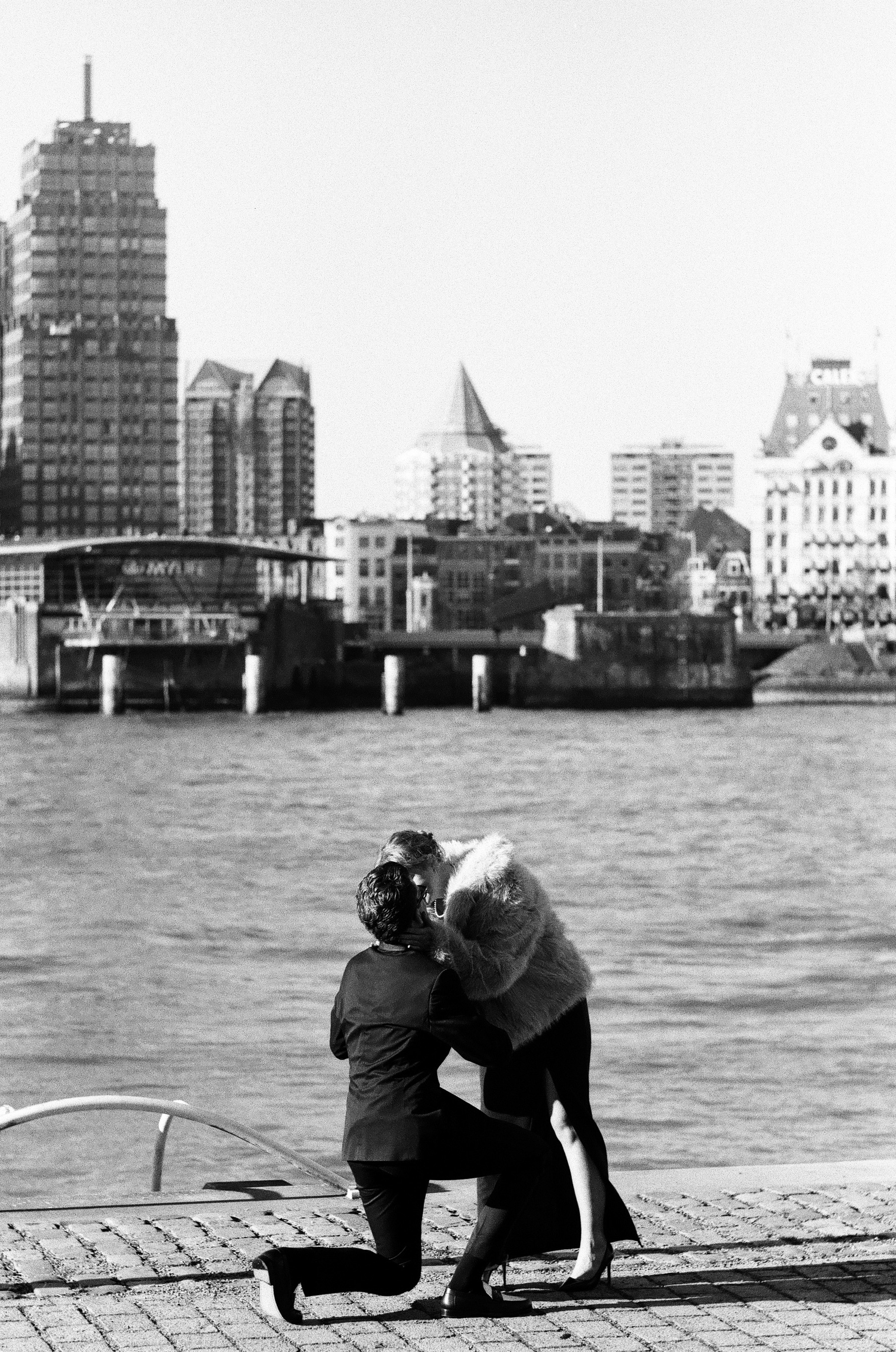 He kneels with the ring while she bends down to hug him, Het Witte Huis across the Maas, a surprise proposal in Rotterdam