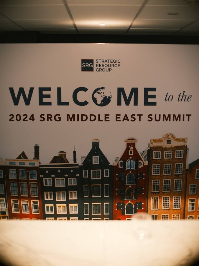 Welkomstbord van de SRG Middle East Summit met het logo van Strategic Resource Group en getekende Amsterdamse grachtenpanden