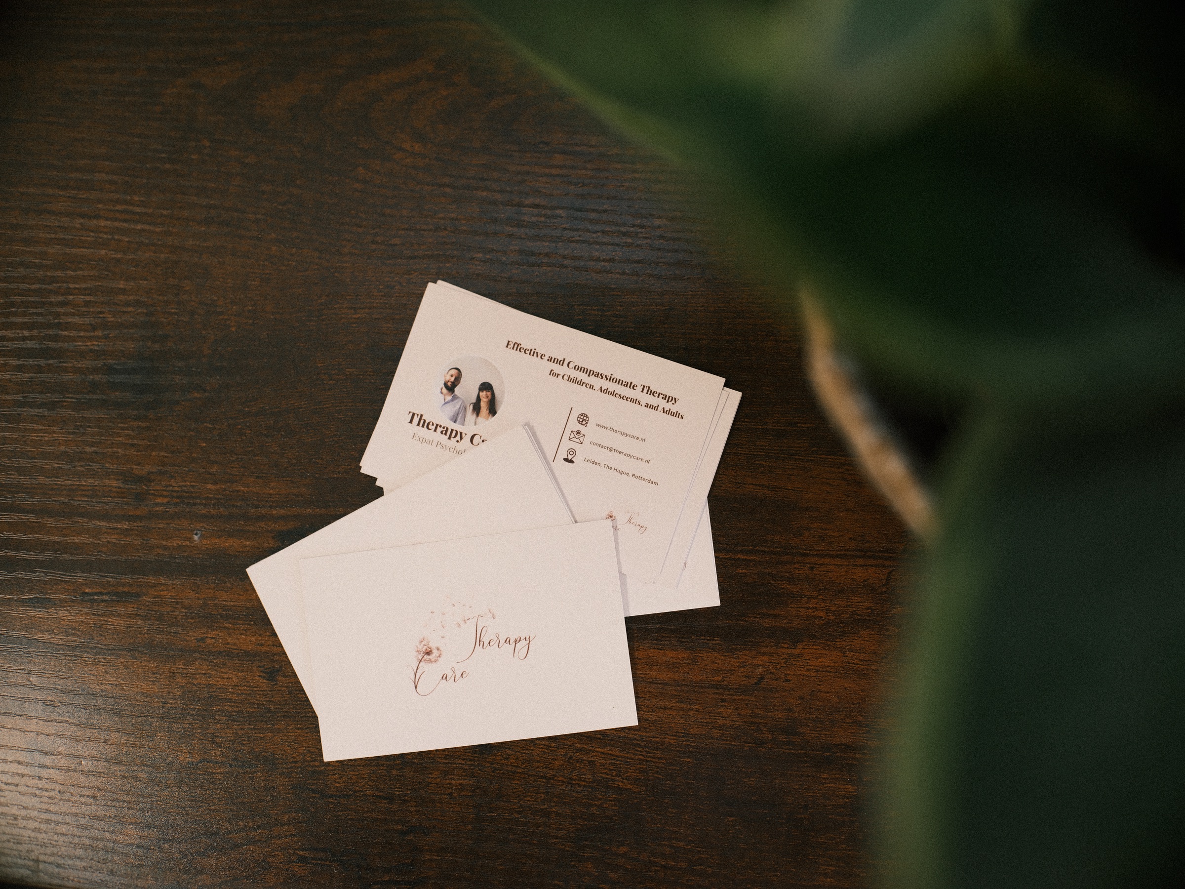 Therapy Care business cards with a dandelion logo on a dark wooden table, a small detail from the branding shoot