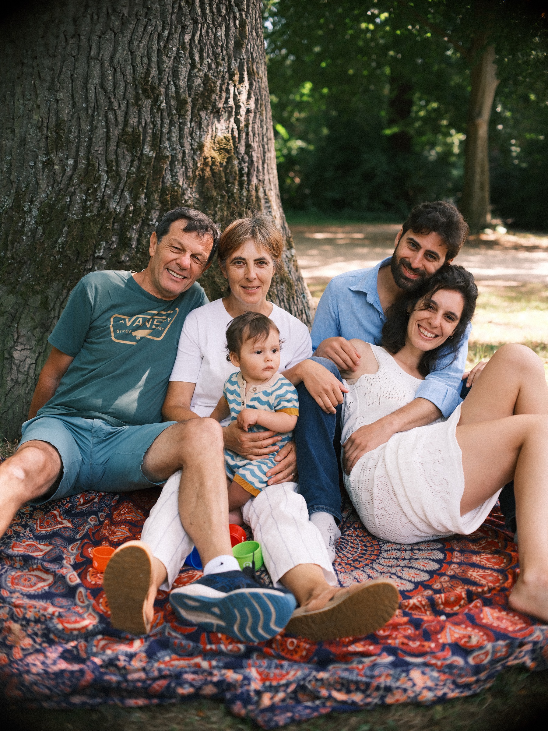 Opa, oma, vader en moeder lachen onder de boom met de baby bij oma op schoot, het laatste beeld van de picknick in Haarlem